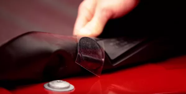 A hand folding a Bed Liner to reveal a Velcro pad on the underside